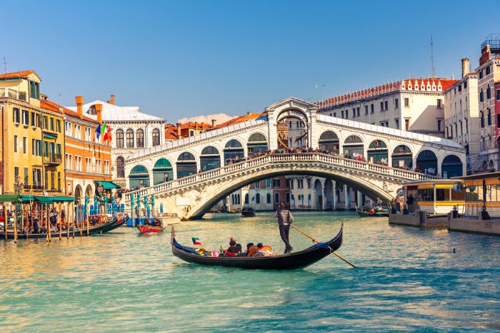 Rialto Bridge in Venice with a tradional gondola floating underneath